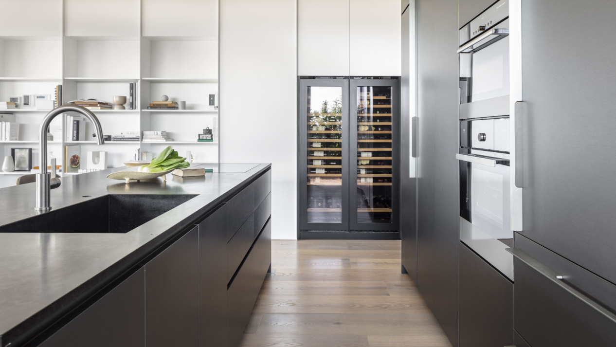 Decorative inspiration. Kitchen renovation. Glazed wine fridge integrated into a made-to-measure kitchen unit with an anthracite gray wooden front to underline and highlight it.