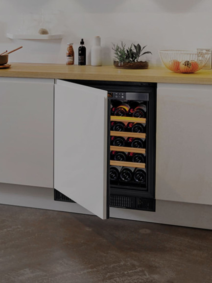 Compact under-counter wine cooler concealed behind a cabinet door matching the kitchen furniture